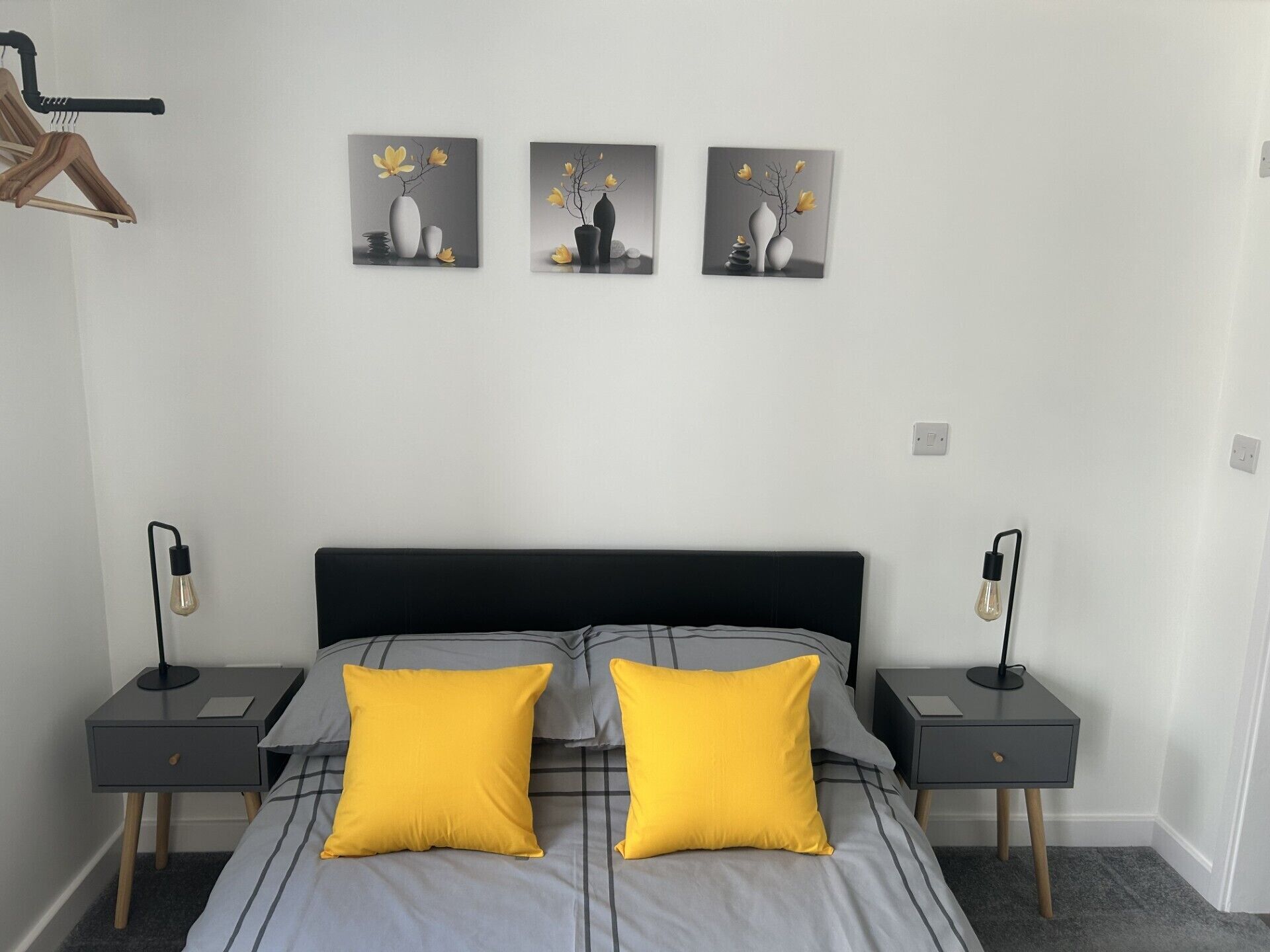 Une chambre à coucher comprenant un lit, deux tables de chevet et trois tableaux accrochés au mur.