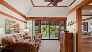 A living room with a sofa, chairs, a glass coffee table, a wooden cabinet, and a ceiling fan. - Kauai Kiahuna Plantation #418 1 Bedroom Condo (Koloa)
