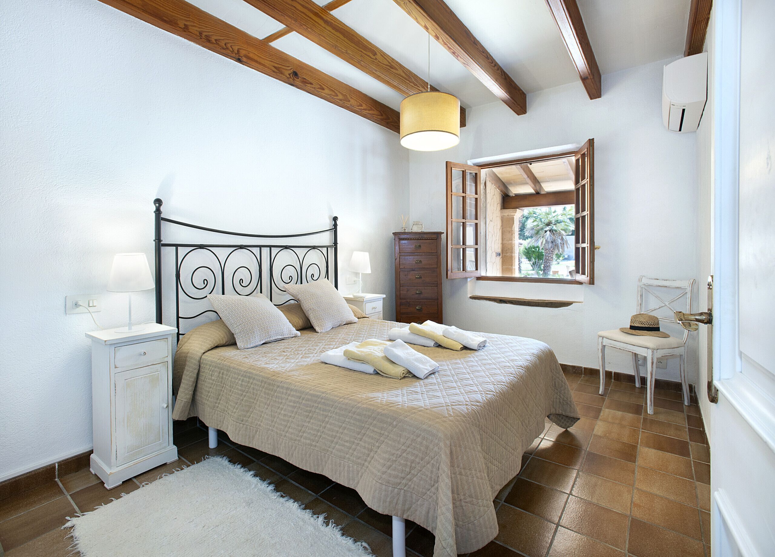 A bedroom with a bed, nightstands, a dresser, a window with a view, and a chair.
