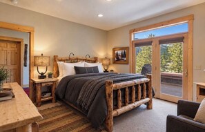 Ein Schlafzimmer mit einem großen Bett, einem Holzkopfende, Nachttischen und Blick durch eine Glastür.