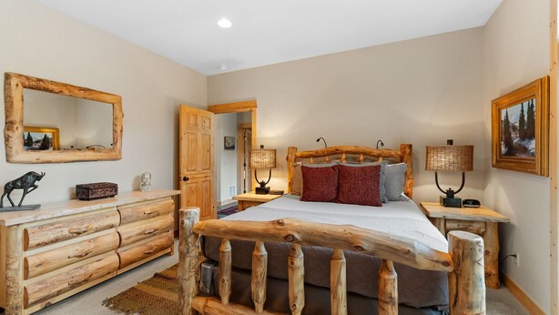 Ein rustikales Schlafzimmer mit einem Holzbettgestell, einem Schminktisch und einem Spiegel.