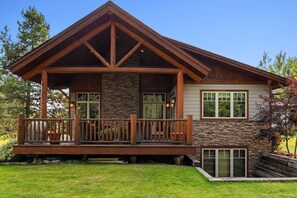 Une maison moderne avec une façade en pierre, une terrasse en bois et une grande fenêtre.