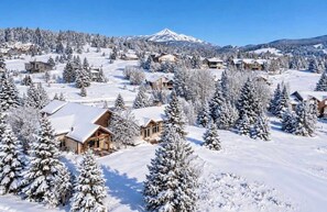 Une ville de montagne enneigée, avec des maisons en bois et un sommet imposant qui se détache à l’arrière-plan.