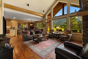 Un salon spacieux doté d’une cheminée, de grandes fenêtres et offrant une vue sur l’extérieur.