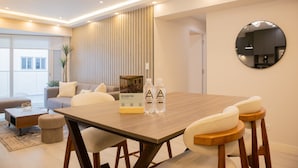 A modern dining area with a wooden table, white upholstered chairs, and a round mirror on the wall. - w Bright 3BR w Balcony in Vibrant Miraflores (Lima)