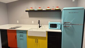 A kitchen with a teal refrigerator, a white sink, and a black faucet.