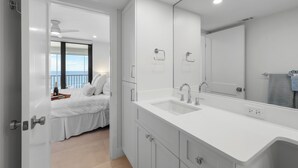Une salle de bain moderne avec un grand miroir, un double vasque et une vue sur le balcon.