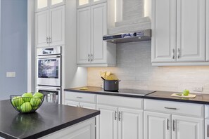 A kitchen with white cabinets, a black countertop, and a stainless steel oven.