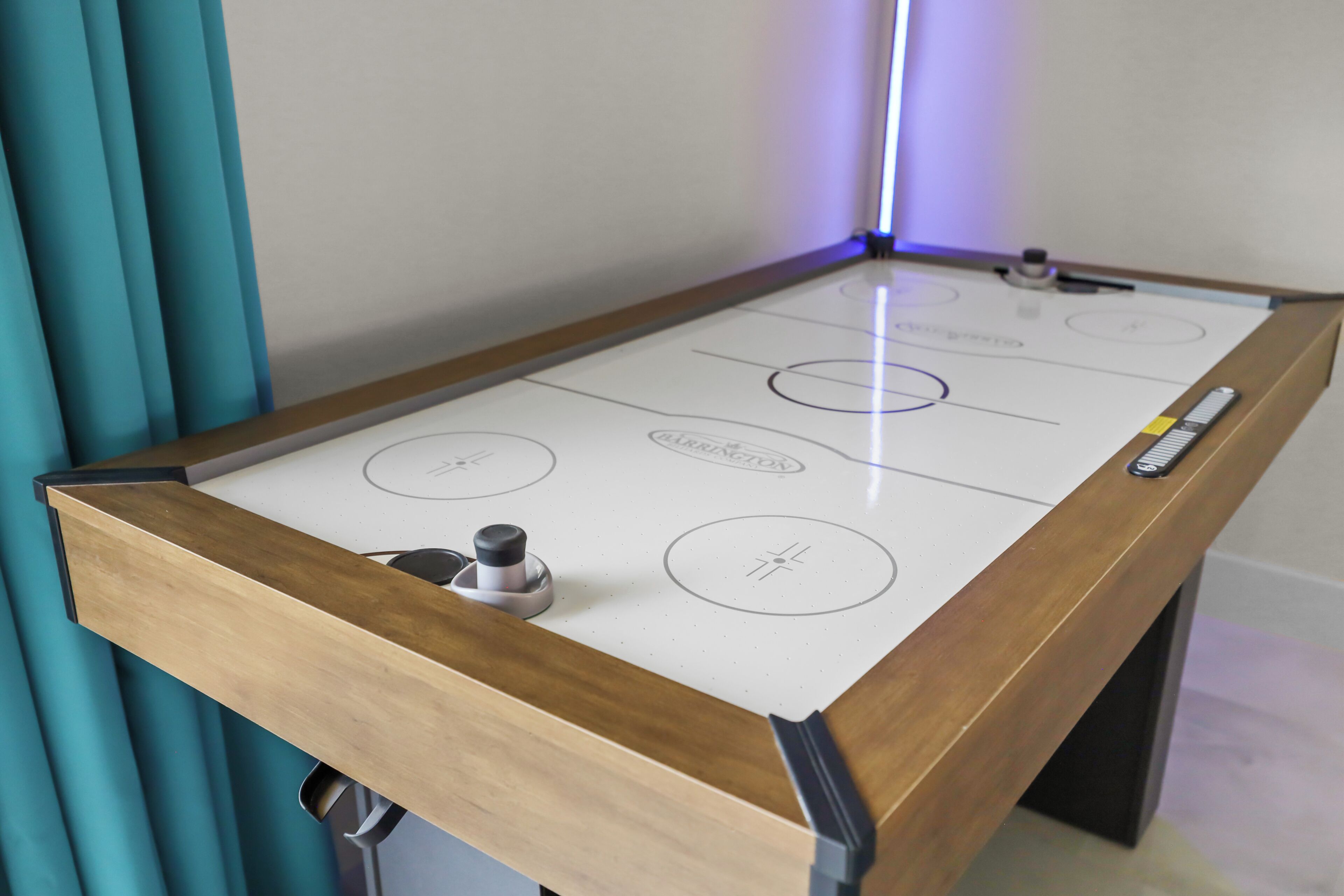 Een pooltafel met houten frame en wit speeloppervlak met cirkelvormige markeringen.