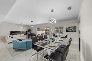 A modern living room with a dining area, a sofa, and a fireplace.