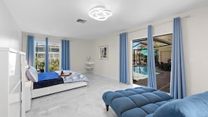 Un dormitorio moderno con cama, un sofá azul y vistas a una zona de piscina al aire libre.