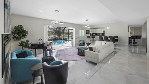 Amplia sala de estar con piscina, muebles modernos y una cocina al fondo.