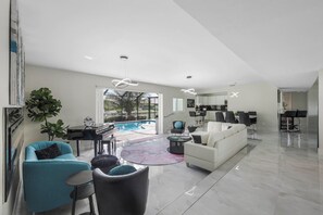 A spacious living area with a pool, modern furniture, and a kitchen in the background.