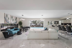 Un salon moderne avec vue sur la piscine, un coin repas et une cuisine.