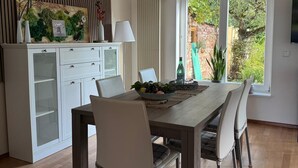 Ein moderner Essbereich mit Holztisch, weißen Stühlen und einer Wanddekoration.