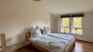 Ein Schlafzimmer mit einem großen Bett, einem Sessel, einem Nachttisch und einer Pendelleuchte.