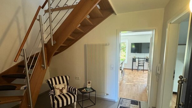 Eine Treppe mit Holzwangen und ein gestreifter Stuhl in einem Wohnbereich.