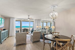 A spacious room with a dining table, chairs, a chandelier, and a view of the ocean. - Charming Coastal Retreat Mag House 410 | Steps to the Beach + Pool Access! (Destin)