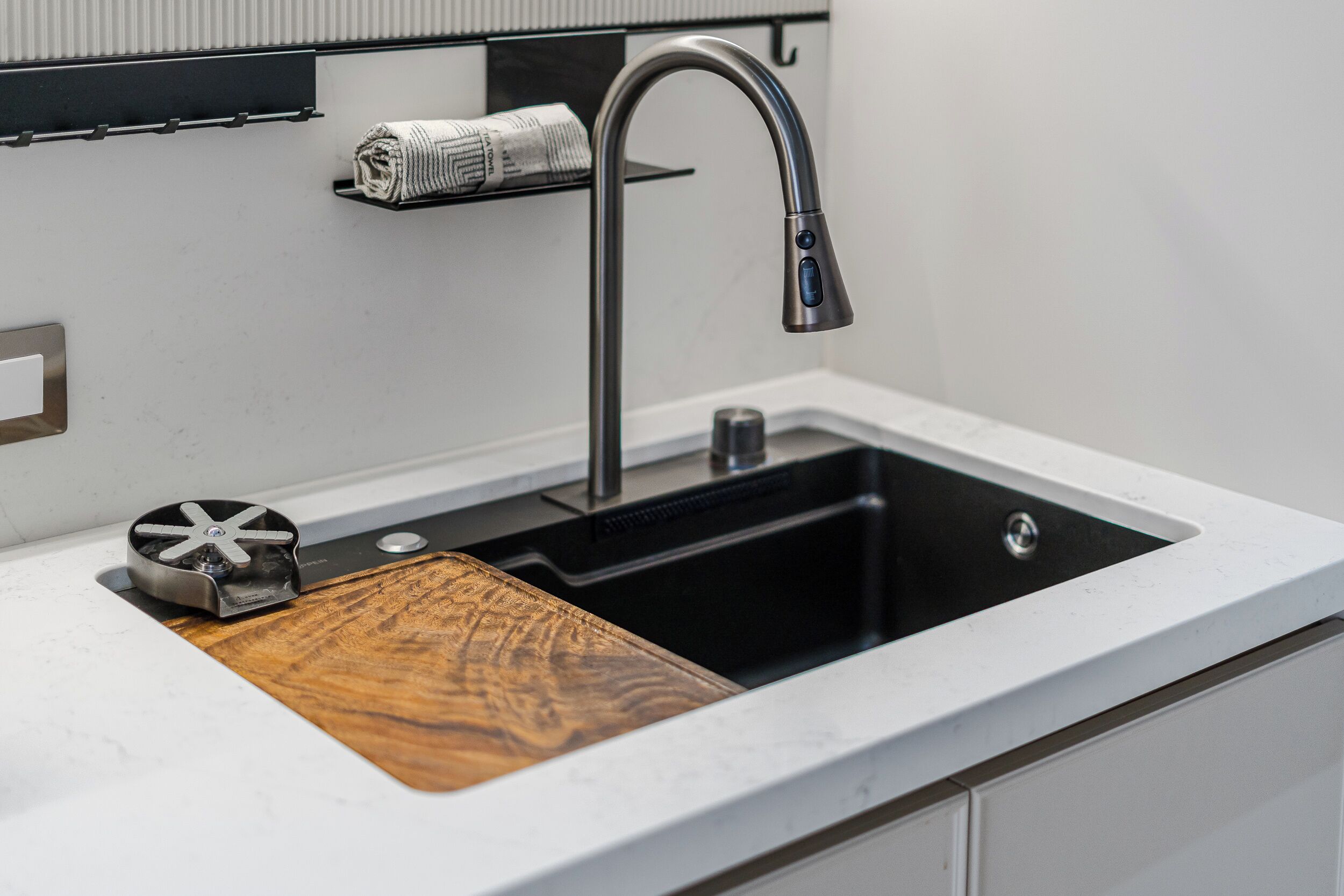 Une cuisine moderne dotée d’un évier en acier inoxydable, d’une planche à découper en bois et d’un porte-rouleau en papier.