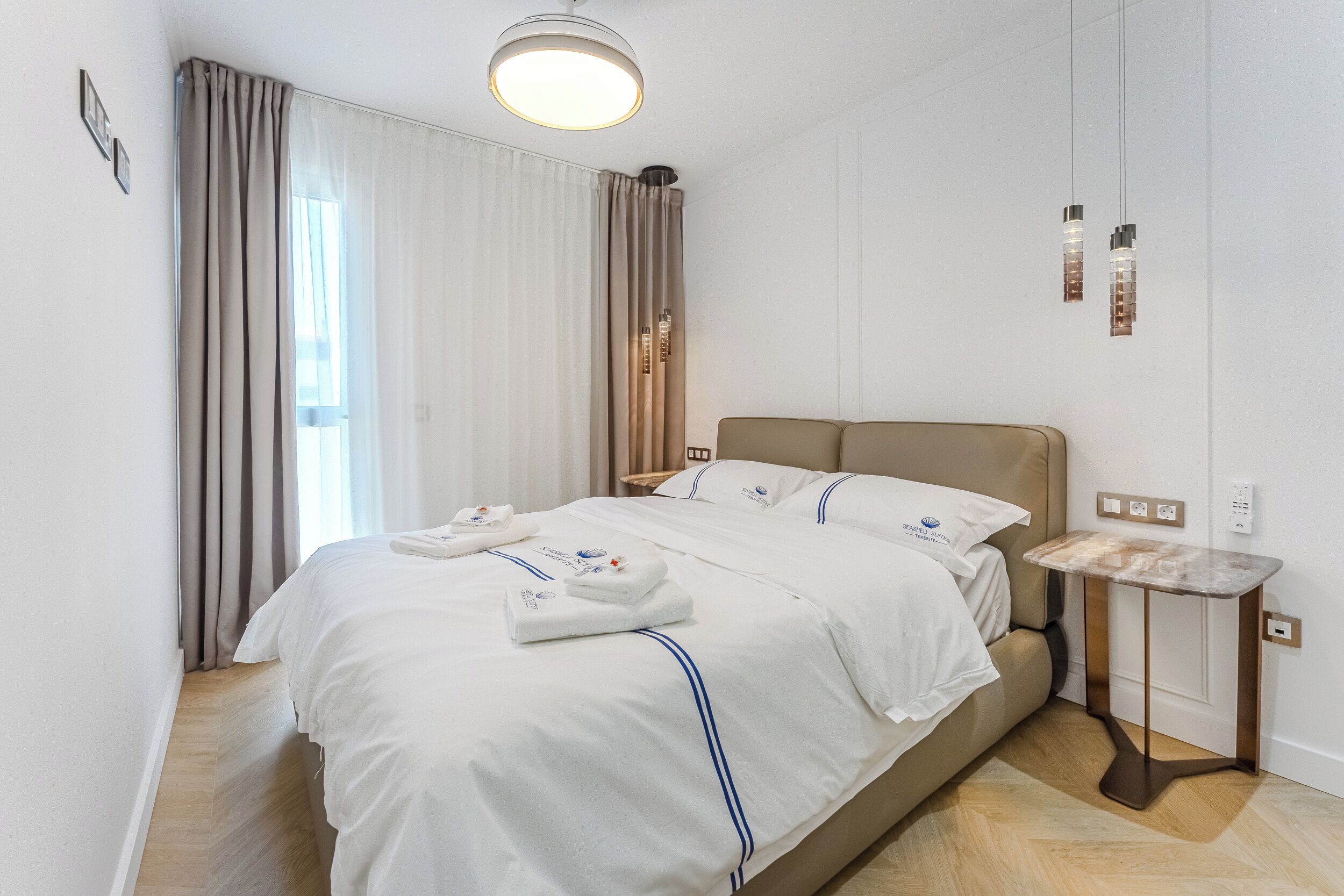 Habitació d'hotel moderna amb un llit gran, una taula de nit i una petita taula auxiliar.