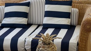 A wicker sofa with striped cushions, a woven vase, and a striped pillow on a table. - Hotel Murè (Numana)