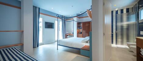 Un dormitorio moderno con cama, escritorio y baño visible a través de una puerta abierta.