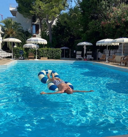 Una piscina al aire libre de temporada, sombrillas