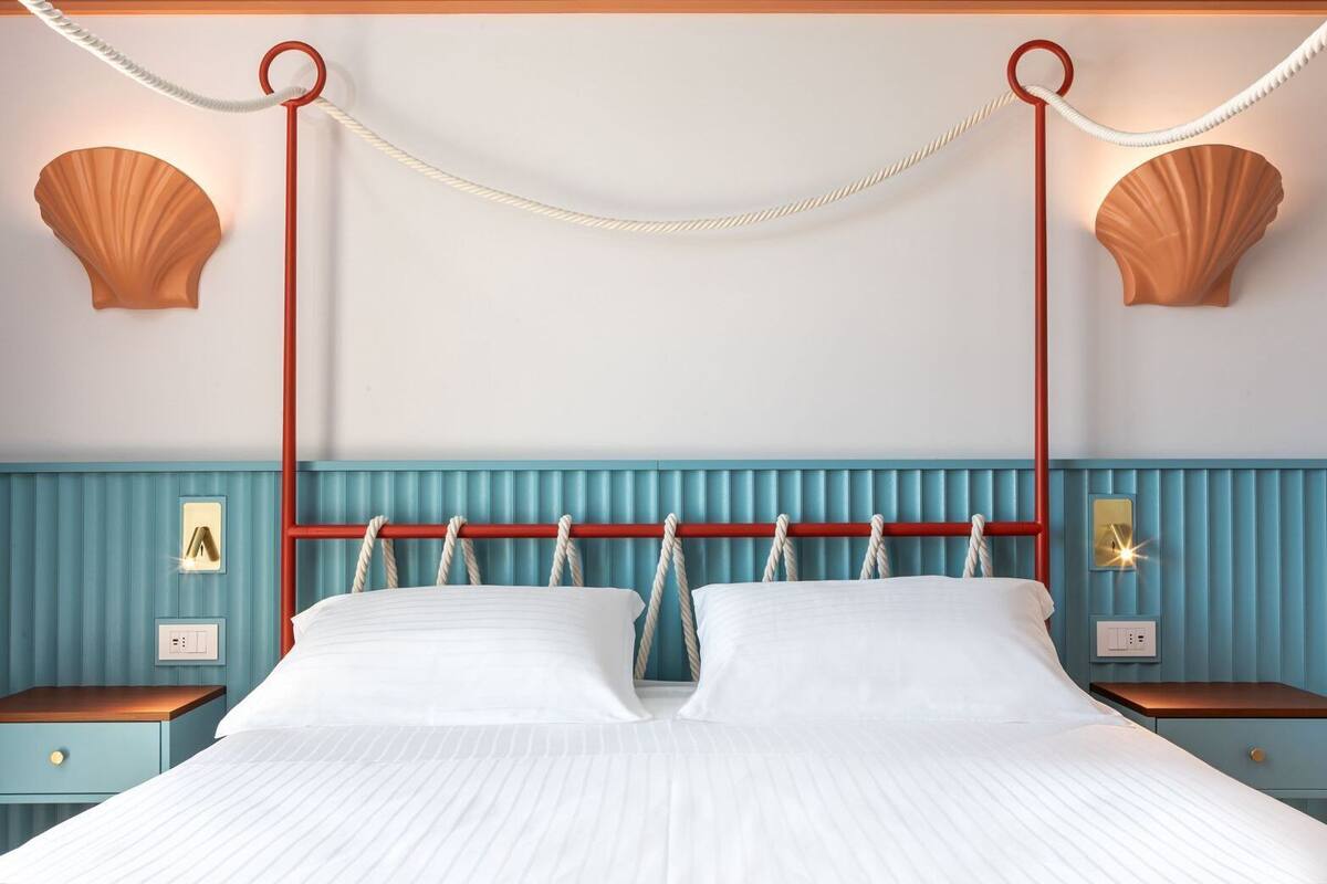 A bed with a red headboard, white bedding, and two nightstands with lamps.