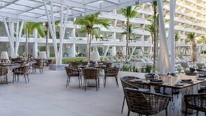 Un comedor interior con mesas y sillas, ventanas amplias y un diseño arquitectónico moderno.