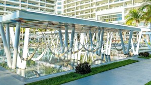 Un hotel moderno con un atrio de cristal y una zona de piscina.