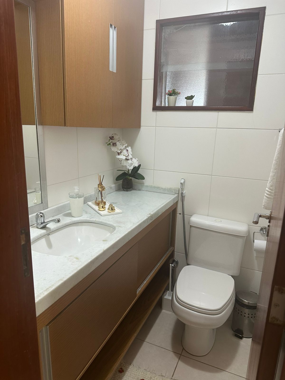 A bathroom with two sinks, a toilet, a mirror, and a small potted plant on the wall.