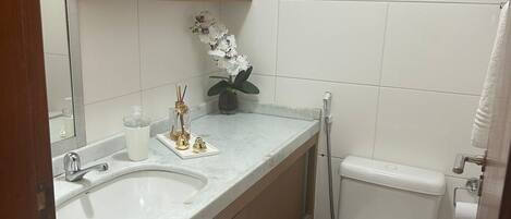 A bathroom with two sinks, a toilet, a mirror, and a small potted plant on the wall.