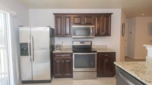 Una cocina con gabinetes de madera oscura, electrodomésticos de acero inoxidable y encimera de granito.