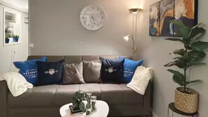 Ett vardagsrum med en soffa, ett soffbord, en klocka, en lampa och en tavla.