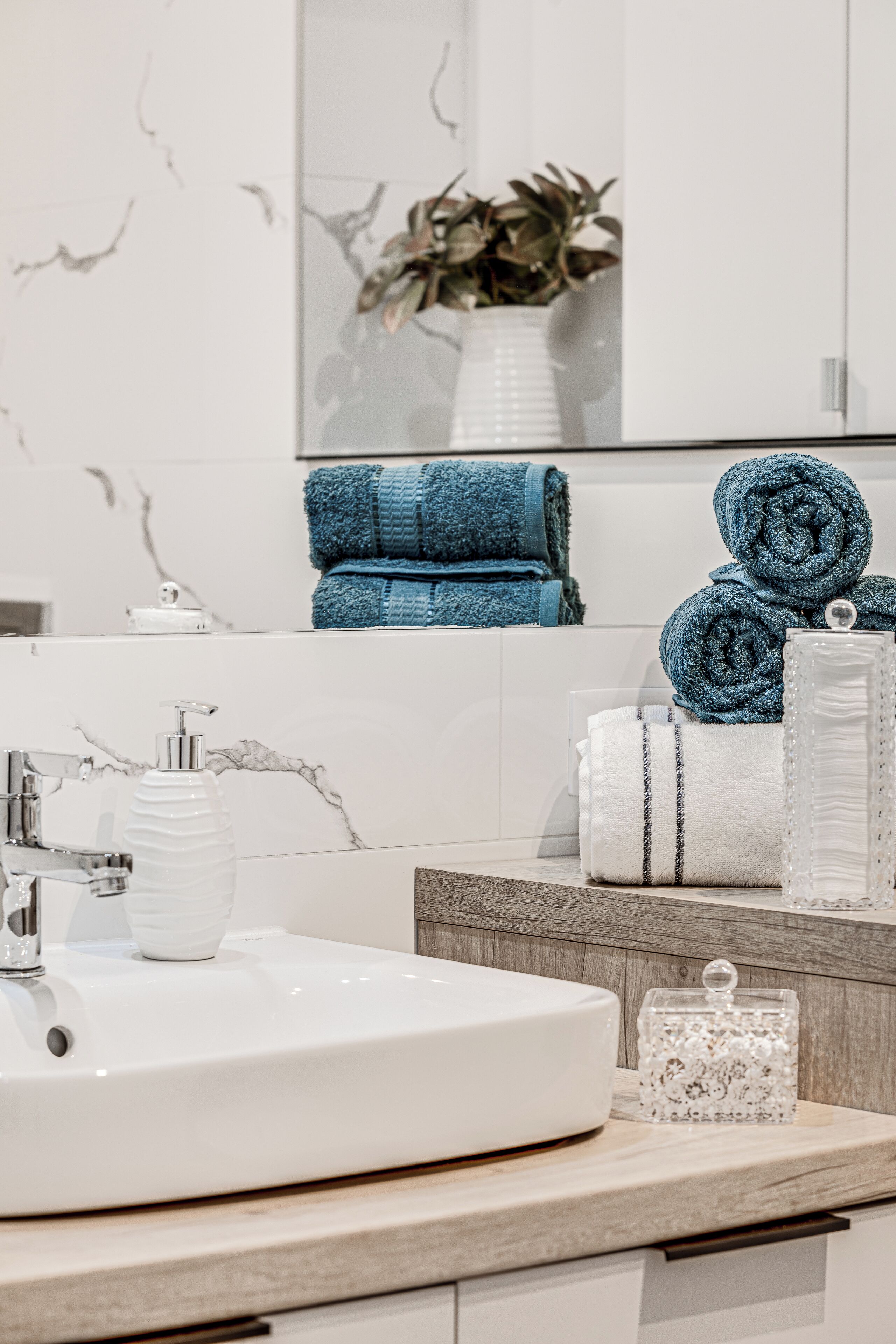 A modern bathroom with a white sink, a marble backsplash, and a wooden vanity.