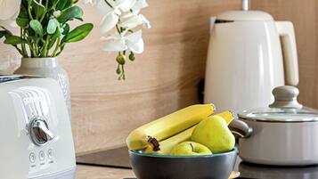 A kitchen with a white toaster, a bowl of fruit, and a white coffee maker on the counter.