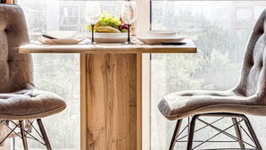 A dining area with a wooden table, two chairs, and a window with curtains. - ARI - AFI Mall Luxurious Apartments (Arad)