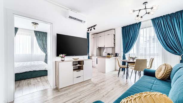 A modern living room with a sofa, TV, and kitchen area. - ARI - AFI Mall Luxurious Apartments (Arad)