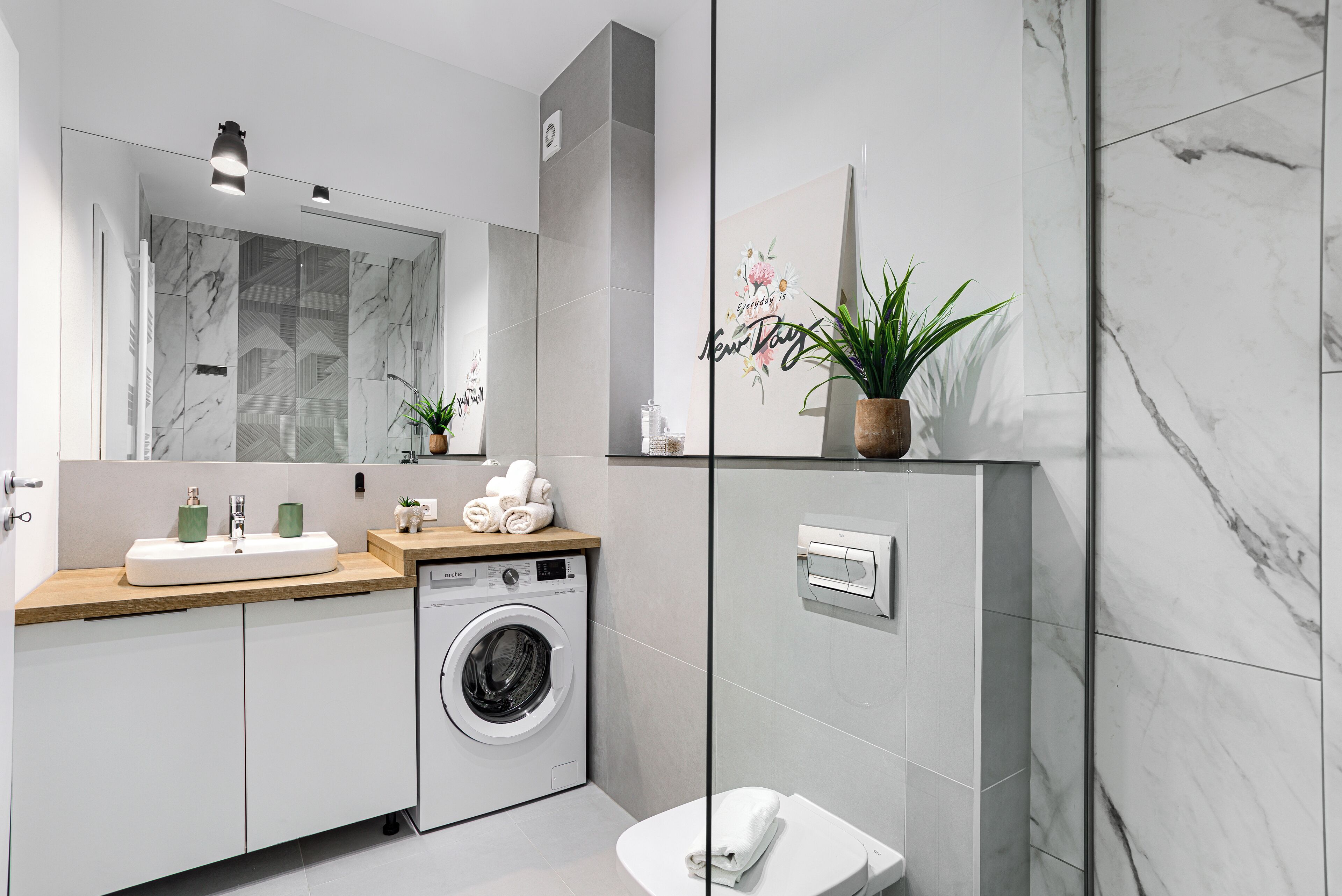 A modern bathroom with a washing machine, a toilet, and a sink.