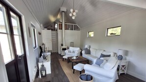 A spacious living area with a white sofa set, a coffee table, and a fireplace. There is a staircase leading to an upper level. - Beachfront holiday home with sea view in Sölvesborg | SE03021 (Sölvesborg)