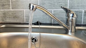 A kitchen sink with a chrome faucet and running water.