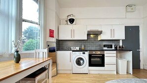 A compact kitchen with a washing machine, microwave, and oven.