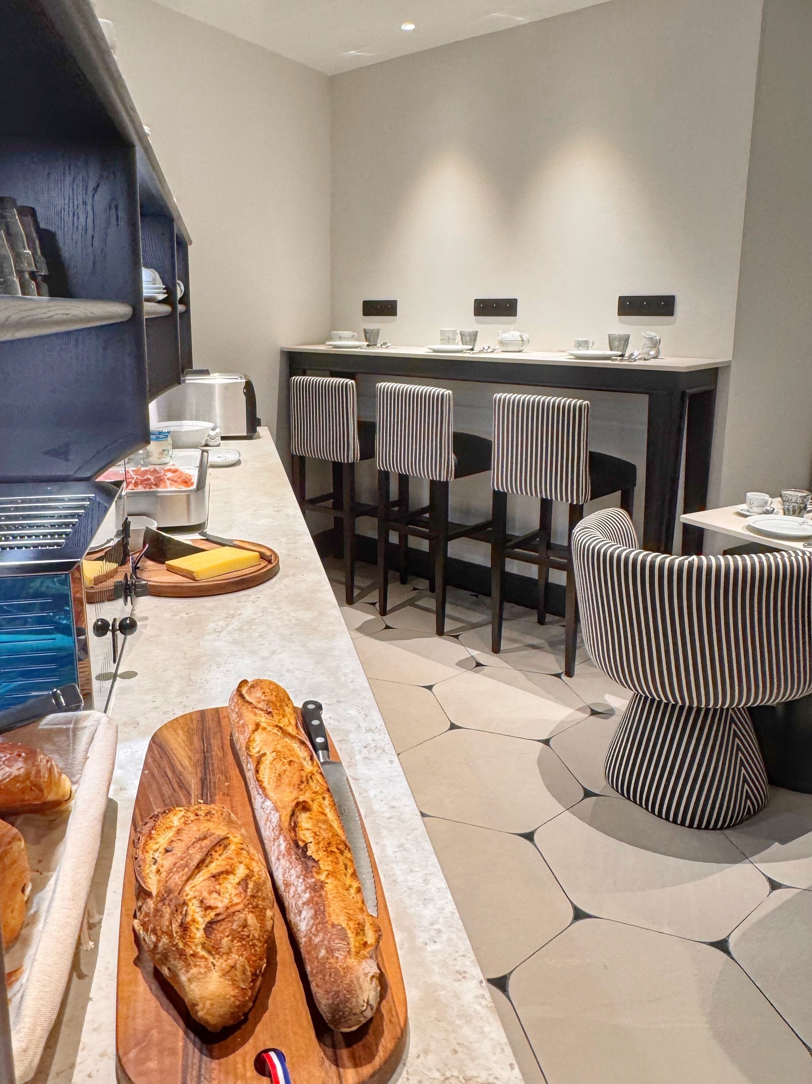 Una cocina moderna con una barra larga, taburetes y una mesa redonda.