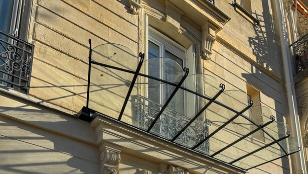 A building facade with a wrought iron balcony, a glass door entrance, and a sign for the Eiffel Yard Hotel. - Eiffel Yard Hotel (Paris)