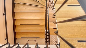 A spiral staircase with wooden steps and metal handrails. - Eiffel Yard Hotel (Paris)