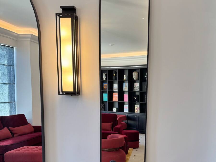Una habitación moderna con un espejo grande, una silla negra y un reposapiés rojo.