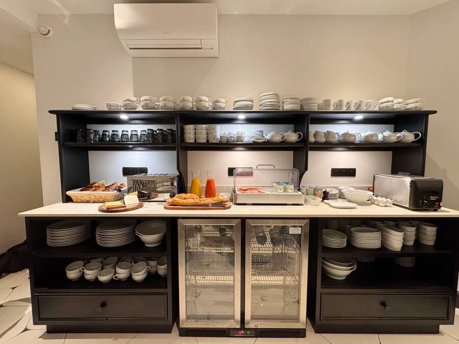 A buffet setup with various food items, utensils, and a refrigerator.