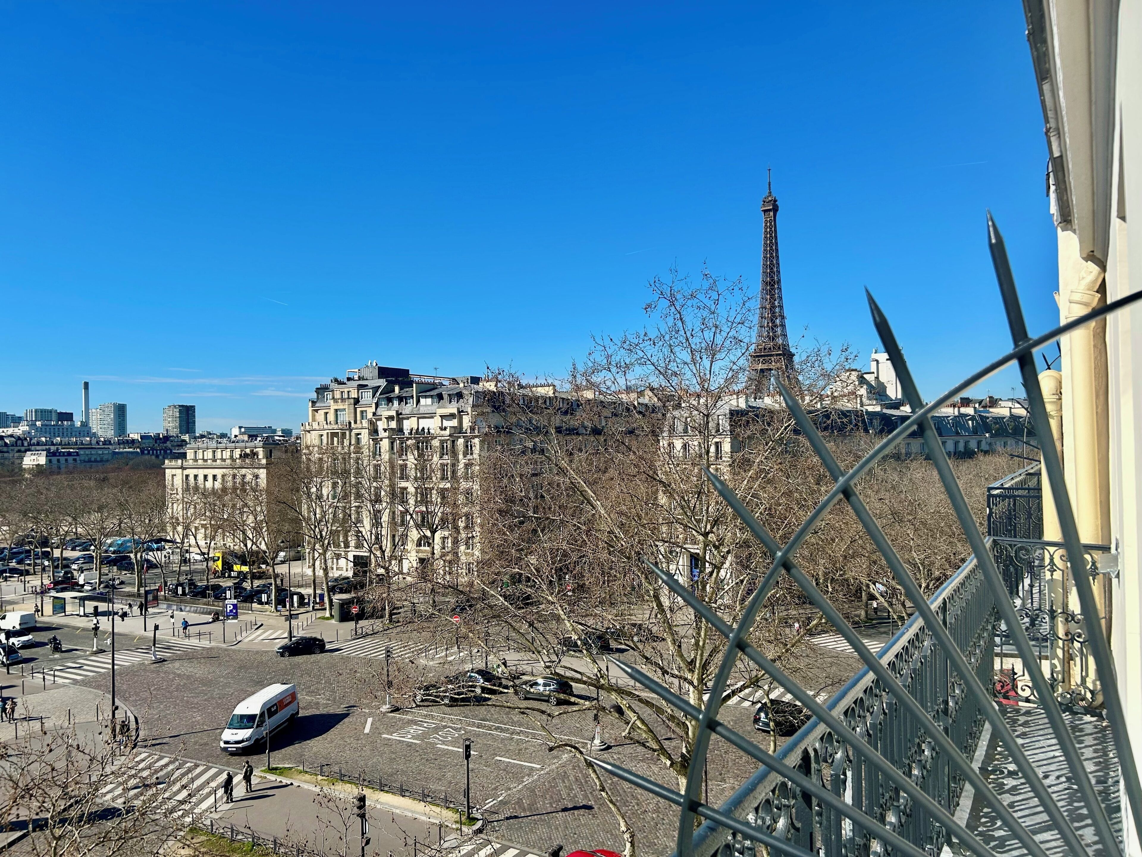 A view of the Eiffel Tower with buildings and a street in the foreground.
