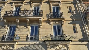 A multi-story building with a classic architectural style, featuring balconies with wrought iron railings, large windows, and a prominent entrance with a glass door. - Eiffel Yard Hotel (Paris)