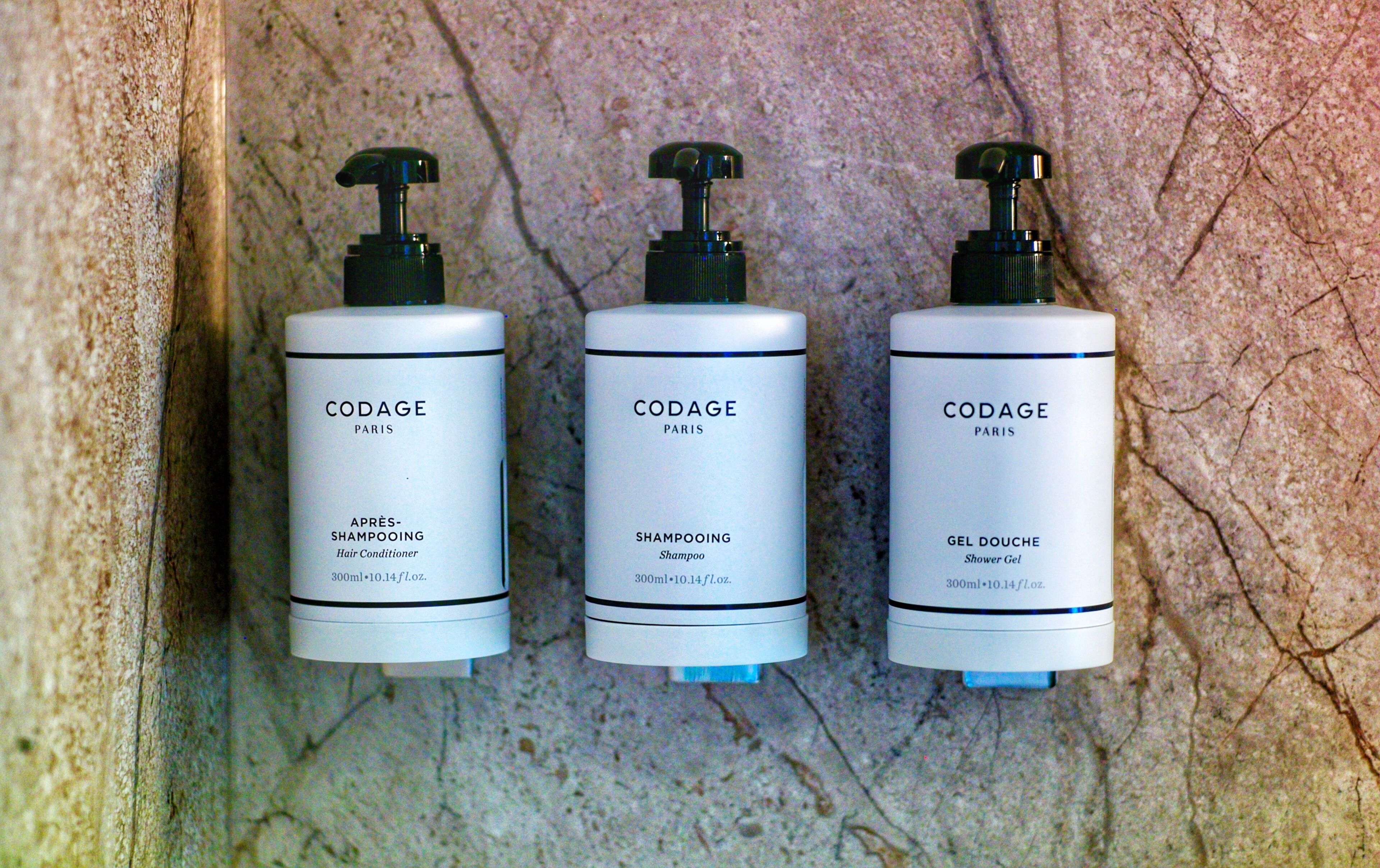 Three CODAGE Paris bottles against a textured wall.